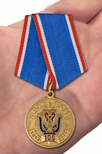 Медаль 100 лет ВЧК-ФСБ в футляре из бордового флока - вид на ладони