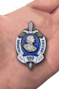 Нагрудный знак "300 лет полиции России" в бордовом футляре из флока - вид на ладони
